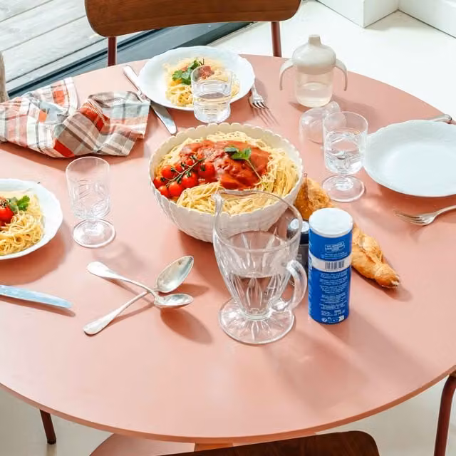 Mesa de comedor redonda Oviala en color rosa para 4 personas con acabado mate y estructura de madera y metal