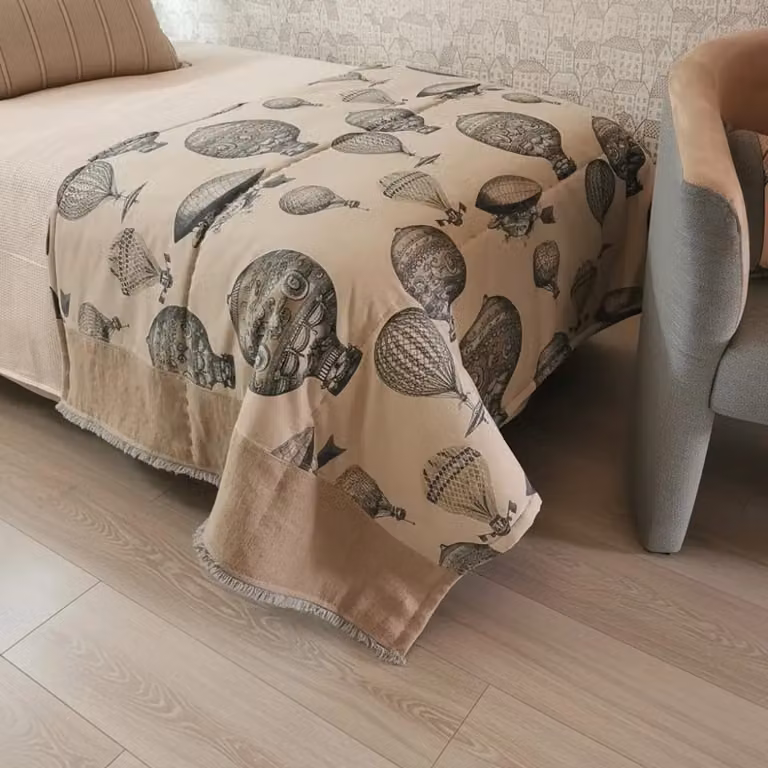 Plaid pie de cama acolchado TAPIDECOR con estampado de globos y flecos en gris, azul y beige para cama de 90 cm