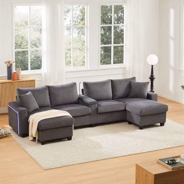 Sofá en U DREAMMESPACE de terciopelo acanalado gris con iluminación LED, puertos USB/Type-C, portavasos y 2 pufs An/P/Al: 334 x 128,5 x 81 cm