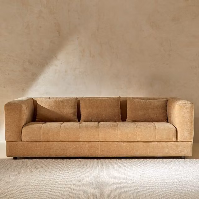 Sofá de 3 plazas Noho El Corte Inglés tapizado en tejido beige con detalles dorados y estructura de madera sólida estilo Chesterfield